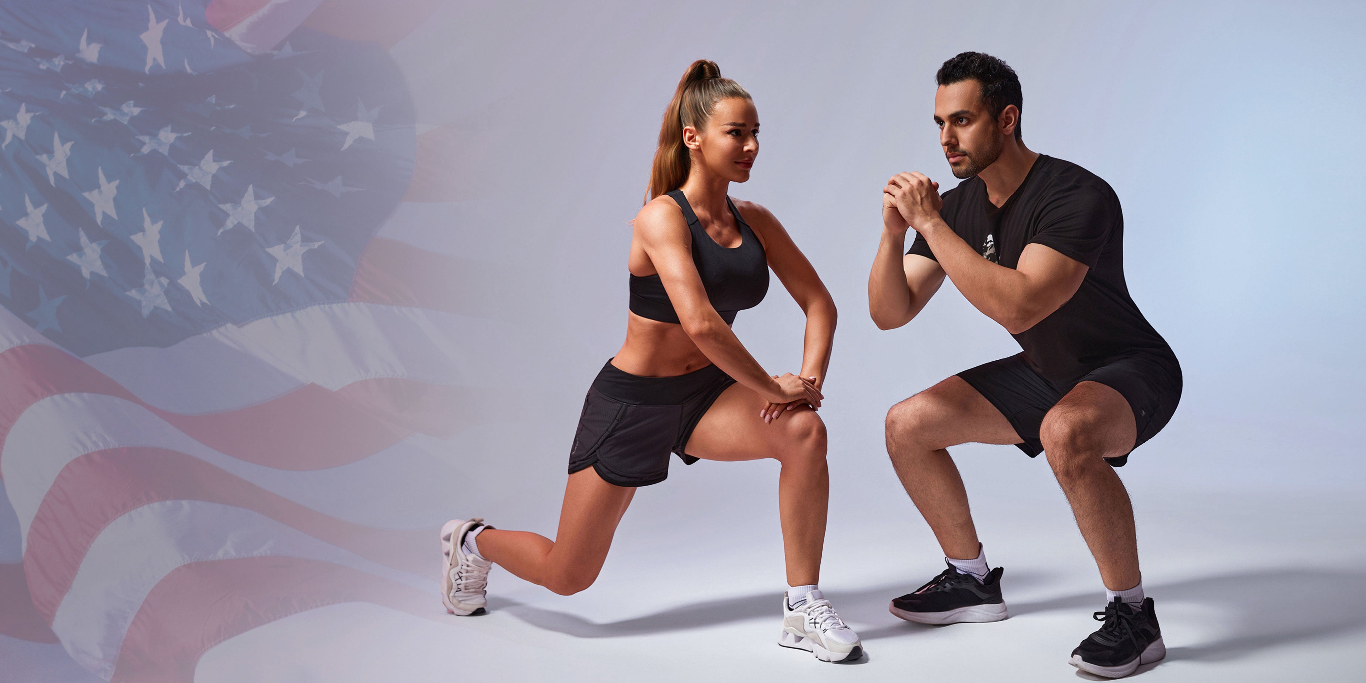 A woman and a man in athletic wear performing lunges and squats, showcasing black HYLETE shorts and workout gear against US flag background.
