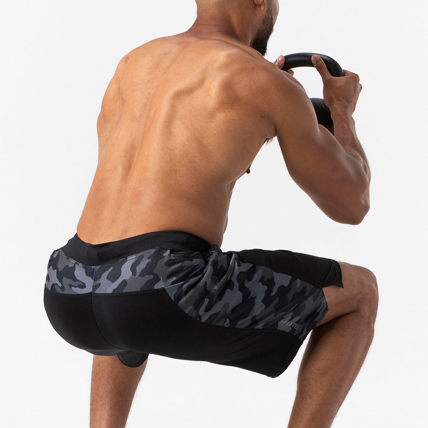 Man performing a squat in Helix III Short Black Camo, showcasing durability and comfort during intense training sessions.