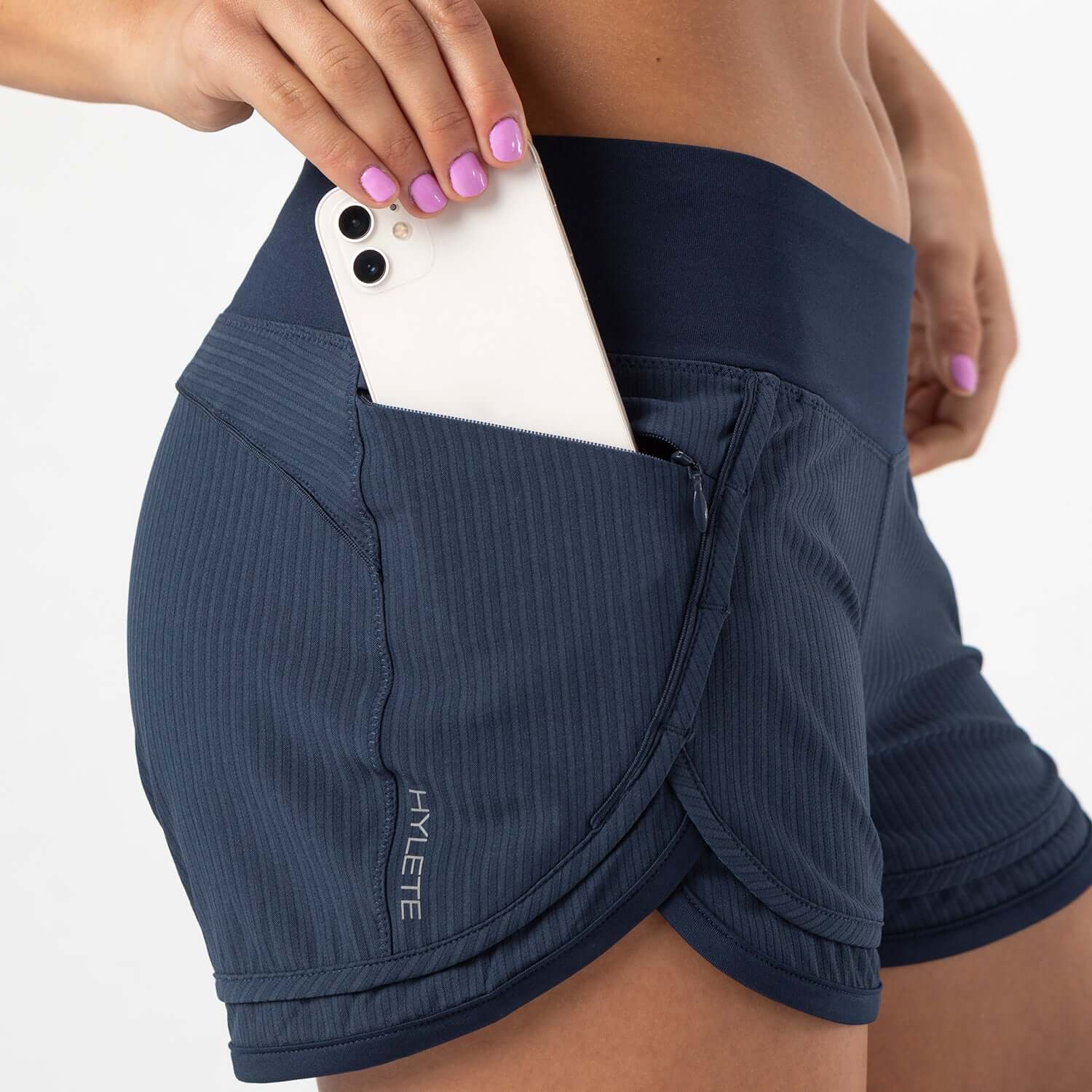 Model wearing Iris Lined Short Classic Navy with phone in pocket, showcasing comfort and functionality for workouts.