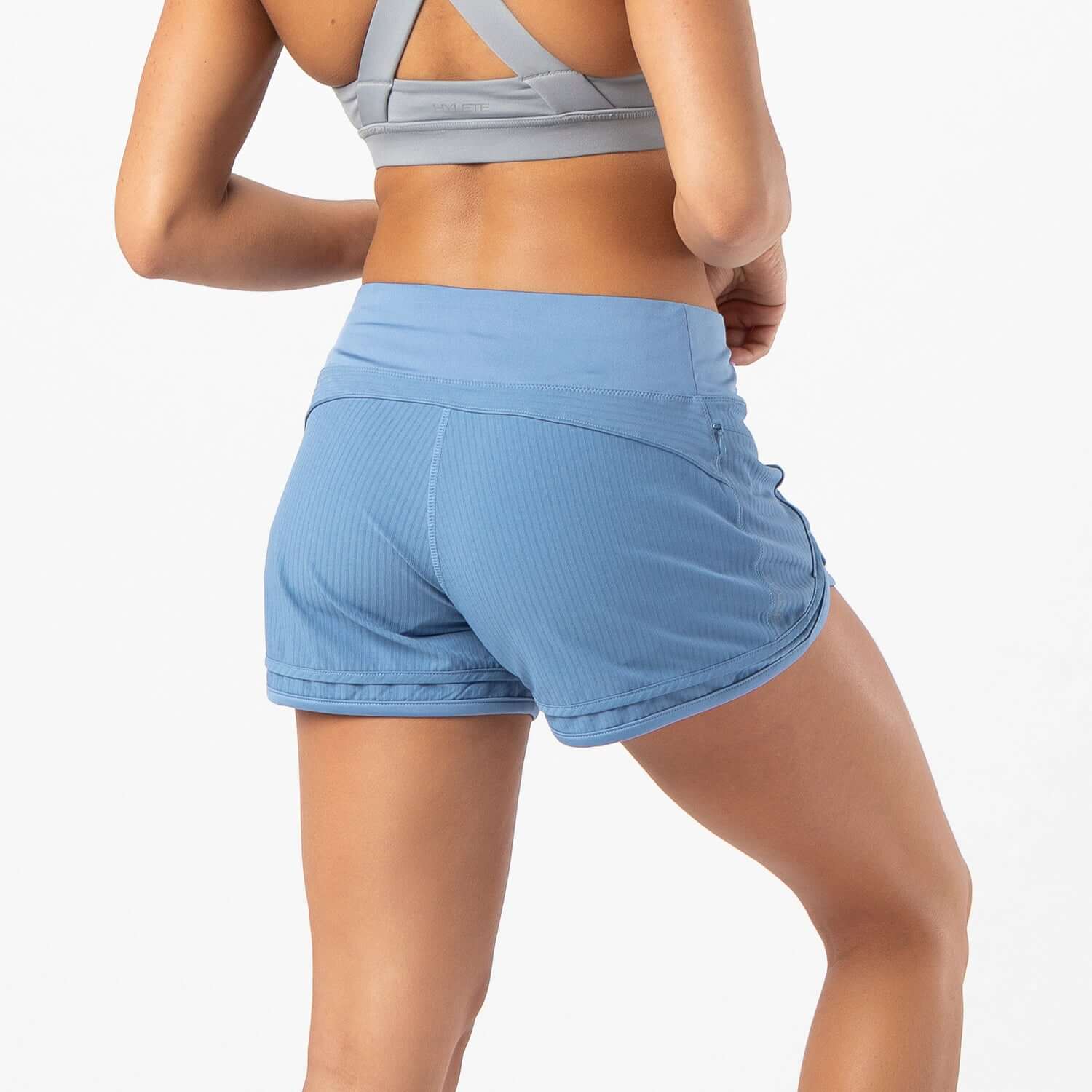 Woman wearing Iris Lined Short in dusty blue, showcasing Flex-Knit waistband and breathable mesh liner for workouts.