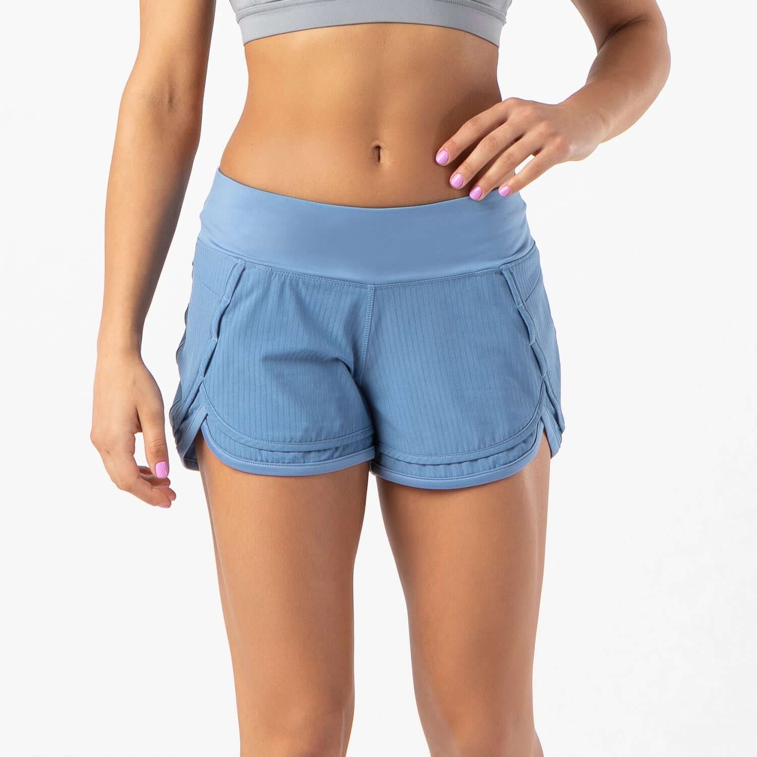Woman wearing Iris lined short in dusty blue, perfect for running and high-intensity workouts with breathable mesh liner.