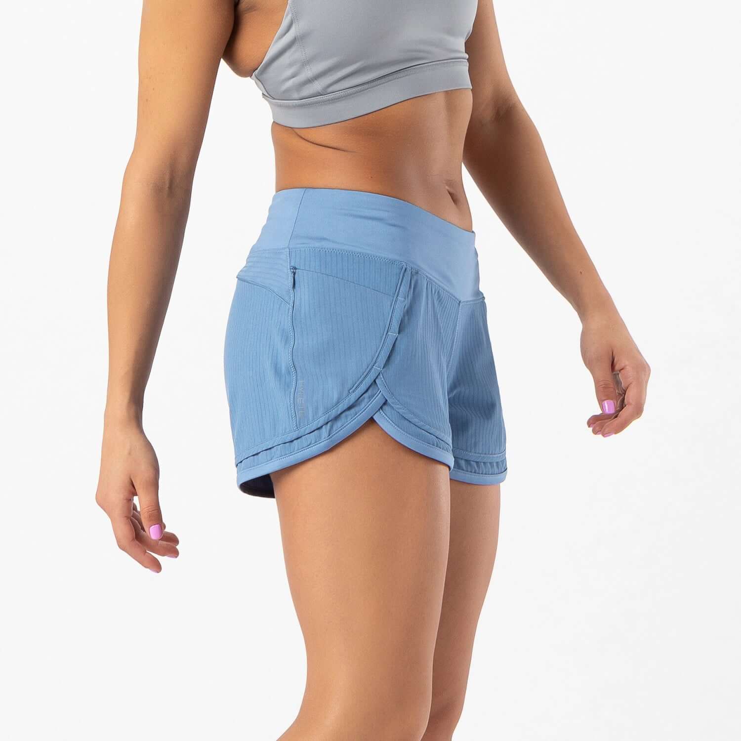 Woman wearing Iris Lined Short in dusty blue, featuring a Flex-Knit waistband and two pockets for active comfort.