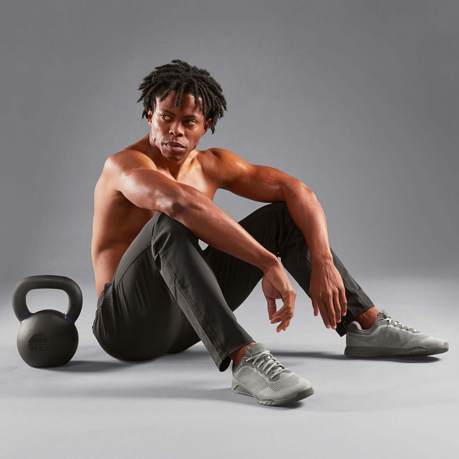 Man in Ion Pant Cool Gray sitting with kettlebell, showcasing comfort and style for gym and everyday wear.