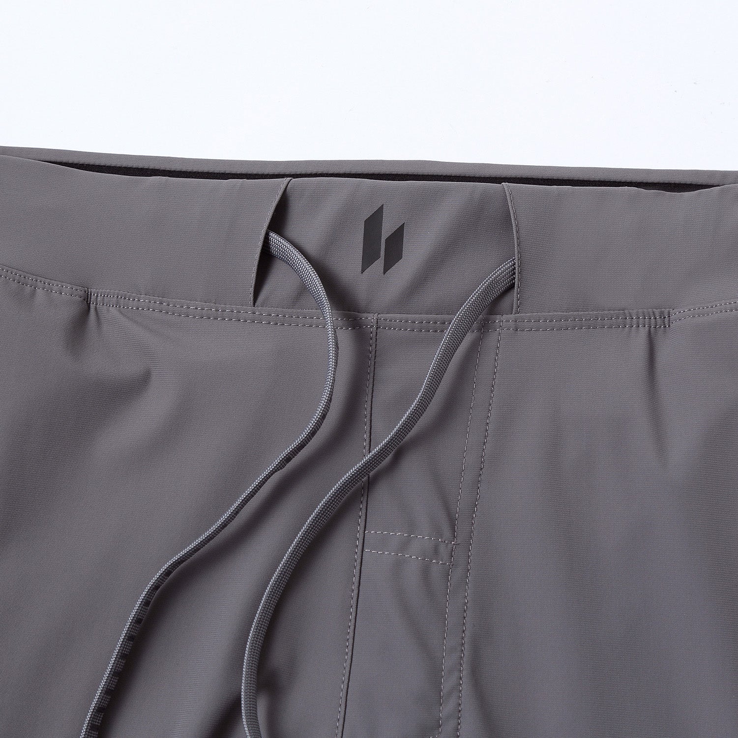 Close-up of HYLTE Ion II cool gray pants with a brand logo on a white background