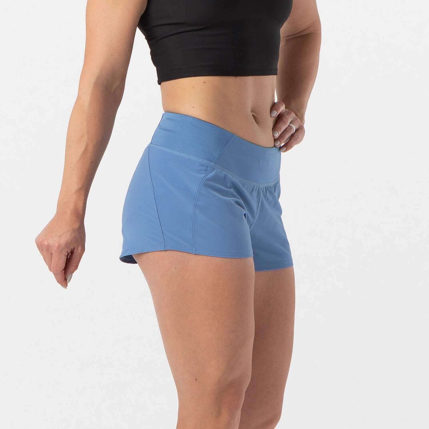 Woman wearing Vita Short Dusty Blue, ideal for runners and HIIT athletes, featuring a smooth-stretch waistband and zippered pocket.