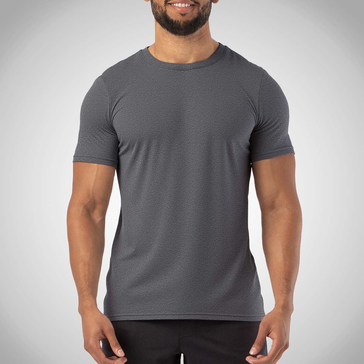 A man with a beard, facing forward, wearing a heather black HYLETE Nexus Crew Tee and black pants.