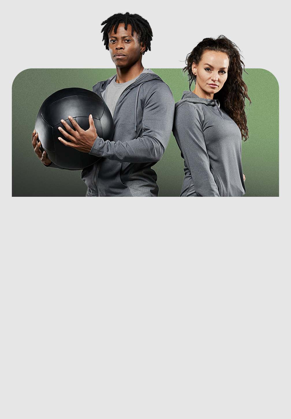 A man and a woman in Hylete gear stand in a gym. The man on the left is holding a black medicine ball.