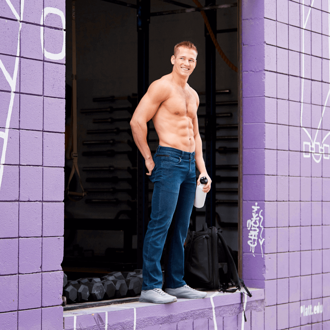 Athletic man wearing Optic II Denim Indigo Stealth Black jeans, showcasing full range of motion in active lifestyle setting.